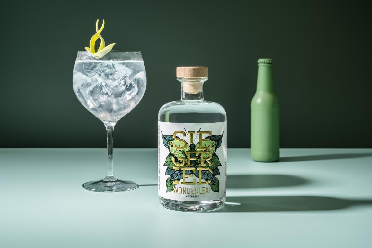 Eine Flasche der alkoholfreien Gin-Alternative SIEGFRIED Wonderleaf mit einem Glas voller Eiswürfel